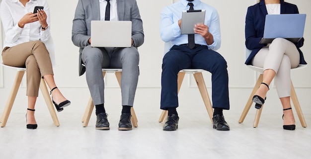 Technologie-Job-Interview und Beine von Geschäftsleuten, die in der Warteschlange für den Rekrutierungsprozess im Büro warten, Human Resources-Treffen und Einstellung von Kandidaten mit Telefon, Laptop und Tablet für die freie Stelle