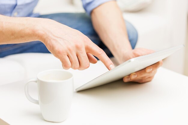 technologie, leute und lebensstil, fernlernkonzept - glücklicher mann mit tablet-pc-computer, der zu hause kaffee oder tee trinkt