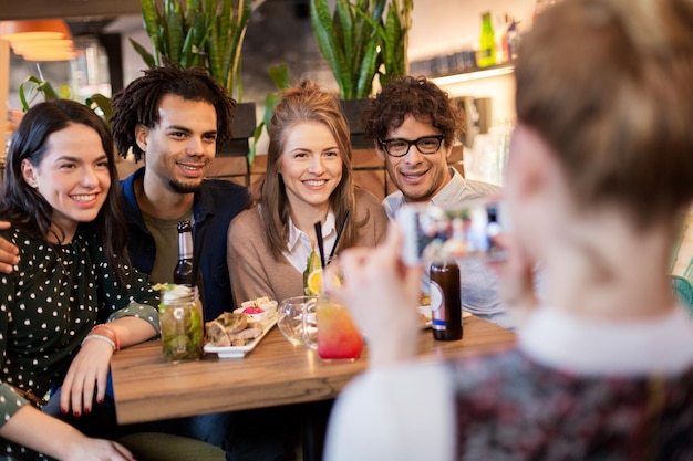 Technologie-, Lifestyle- und Menschenkonzept - glückliche Freunde mit Smartphone-Fotografieren in Bar oder Café