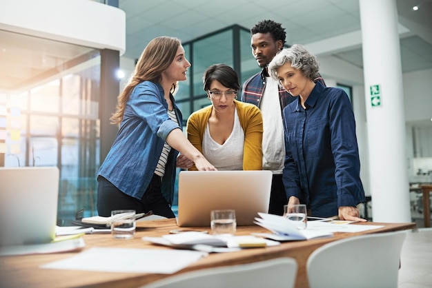 Technologie macht ihre Meetings effizienter Aufnahme eines Teams kreativer Geschäftsleute, die im Büro um einen Laptop herum Brainstorming betreiben