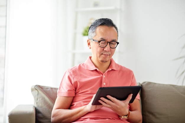 Technologie-, Menschen- und Lifestyle-Konzept - Mann mit Tablet-PC sitzt zu Hause auf dem Sofa