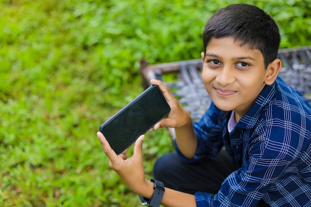 Technologie- und Personenkonzept - lächelnder Teenager im blauen Hemd unter Verwendung des Smartphones