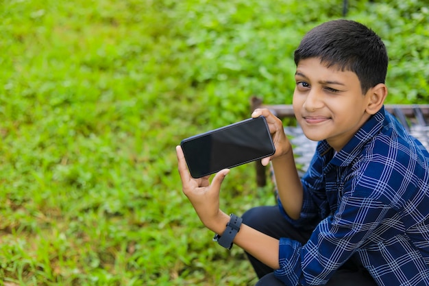 Technologie- und Personenkonzept - lächelnder Teenager im blauen Hemd unter Verwendung des Smartphones