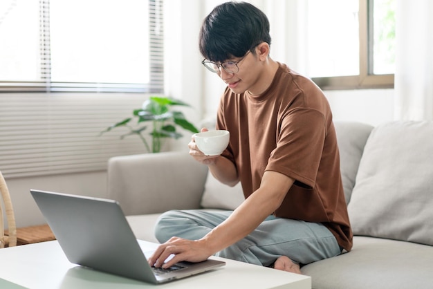 Technologiekonzept Der Mann im braunen T-Shirt, der mit einer Hand auf seinem Laptop tippt