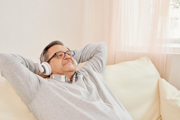 Technologiemenschen und Lifestyle-Konzept Glücklicher älterer Mann mit Kopfhörern, der zu Hause Musik hört