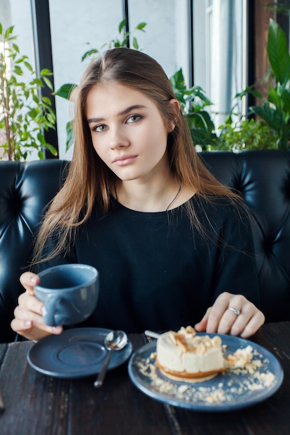 Technologien Emotionen Lifestyle Menschen Teenager-Konzept Junge glückliche weibliche Lesung auf ihrem Handy, während sie in einem modernen Café-Interieur sitzt Mädchen mit schönem Lächeln trinkt Tee