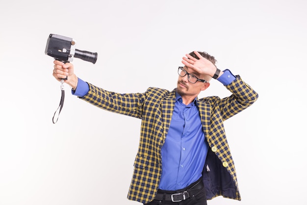 Technologien, Fotografieren und Menschenkonzept - hübscher junger Mann mit Retro-Kamera, der über weißem Hintergrund lächelt.