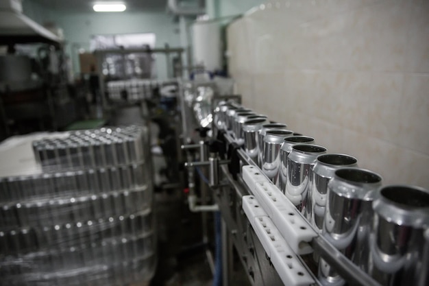 Technologische Linie zum Abfüllen von Bier in der Brauerei Leere Bierdosen aus Aluminium bewegen sich entlang des Förderbandes Saubere Bierflaschen bewegen sich entlang der Produktionslinie der Förderindustrie