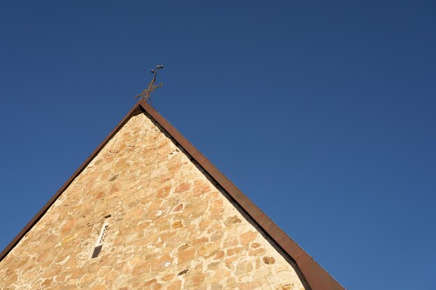 El techo de la antigua iglesia de piedra con un cielo azul de fondo.