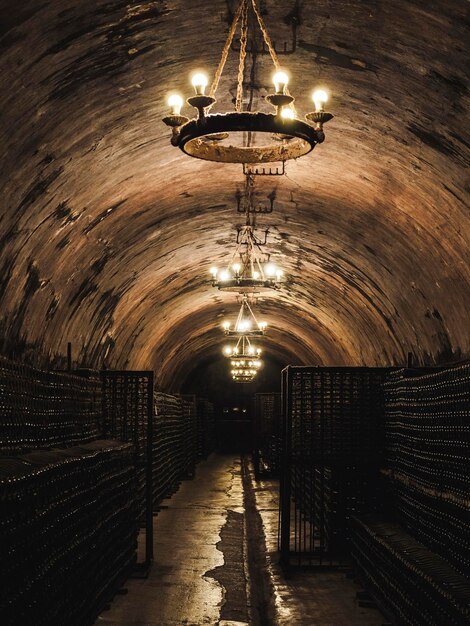 techo arqueado alto con candelabros y filas de botellas de champán en el sótano de una vieja bodega