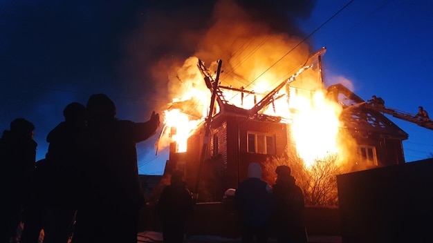 El techo de la casa está en llamas El edificio residencial quema el pueblo Los bomberos apagaron un incendio de la grúa desde arriba Humo y chispas