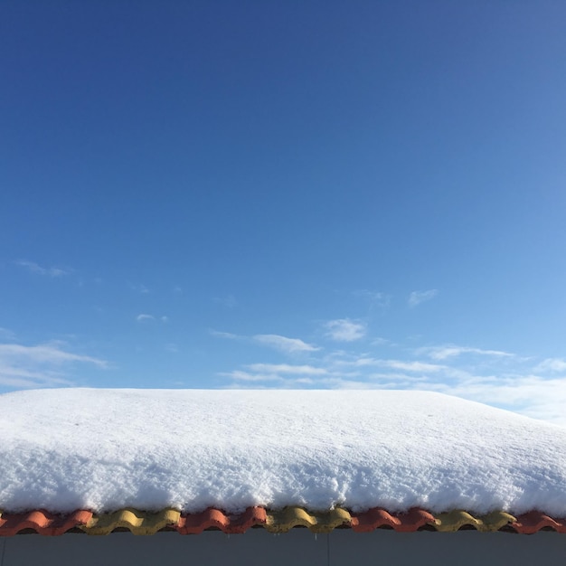 Foto techo cubierto de nieve contra el cielo azul