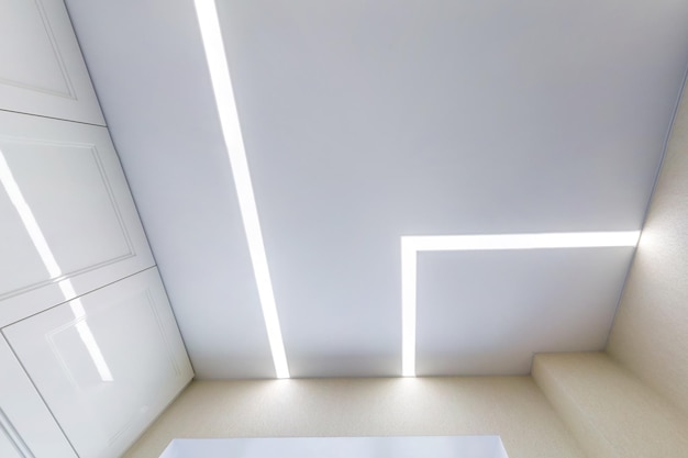 Techo suspendido con lámparas halógenas y construcción de paneles de yeso en una habitación vacía en un apartamento o casa Techo tensado blanco y forma compleja
