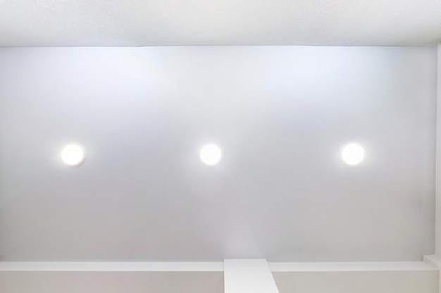 Foto techo suspendido con lámparas led y construcción de paneles de yeso en una habitación vacía en un apartamento o casa techo tensado blanco y forma compleja mirando hacia arriba