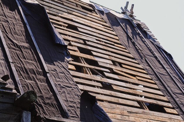 Techo de tablero de madera roto y material de techo roto de la casa vieja en el pueblo necesitan reparación