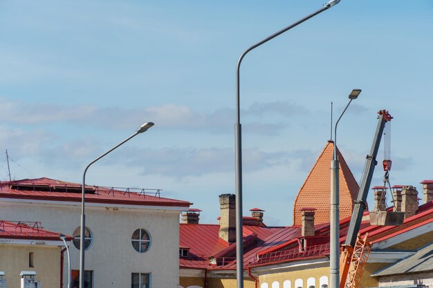 Los techos de las casas en la ciudad con lentejas rojas Una grúa torre está operando cerca de la casa que necesita reparación de la fachada Un sitio de construcción