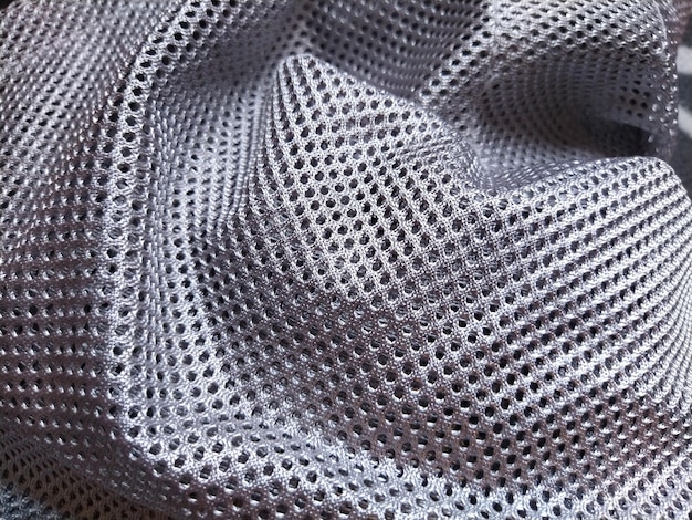 Tecido de poliéster sintético com furos Fundo abstrato Um pedaço de tecido ondulado na cor cinza ou prata