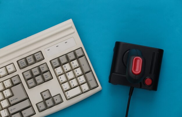 Dois gamepads retrô e teclado de pc antigo em fundo vermelho. jogos,  competição de videogame. vista do topo