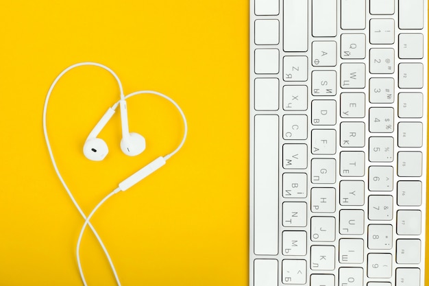 Teclado y auriculares en forma de corazón en el escritorio amarillo.