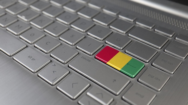 Foto el teclado con la bandera de guinea en el botón de entrada representa el lenguaje de aprendizaje de ataque cibernético