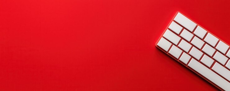 El teclado blanco moderno sobre un fondo rojo vibrante crea un sorprendente contraste visual perfecto para temas relacionados con la tecnología o el diseño digital