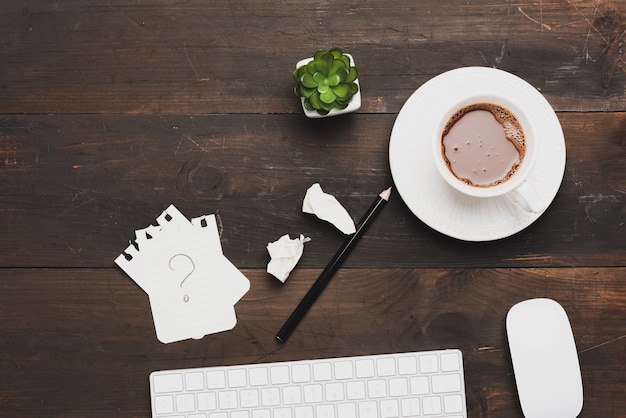 Teclado branco sem fio e xícara de café em uma mesa de madeira marrom, vista superior, local de trabalho