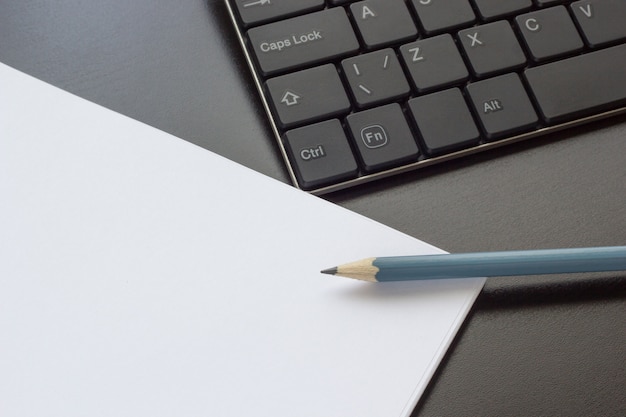 Teclado, caderno e lápis sobre a mesa, vista superior