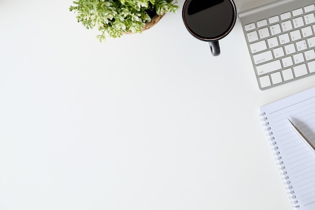 Teclado, café, bloco de notas e lápis de computador da mesa de escritório na opinião superior do espaço de trabalho.