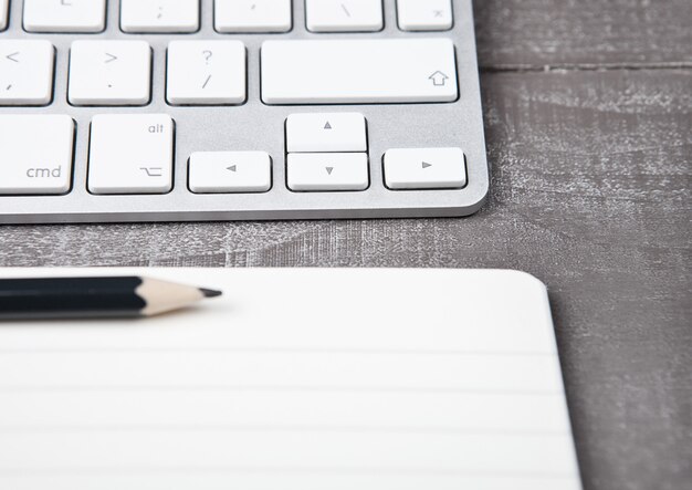 Teclado com lápis no caderno aberto na mesa de escritório