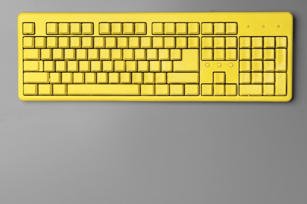 Teclado de computadora amarillo sobre fondo gris