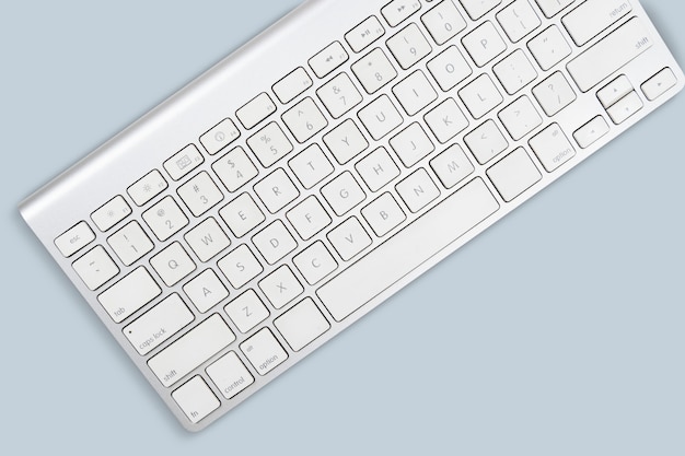 Teclado de computadora blanco sobre fondo gris cielo con espacio de copia