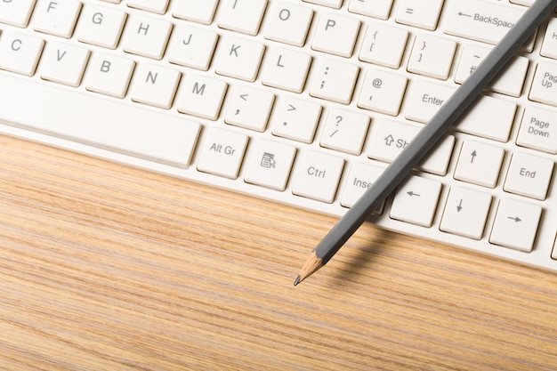 Teclado de computadora y lápiz en la mesa, vista superior