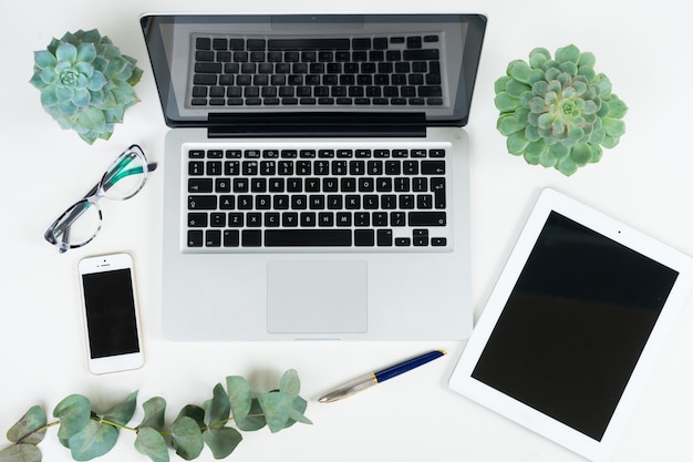 El teclado de la computadora portátil con accesorios de mujer dorada y plantas verdes simulan una escena de estilo plano