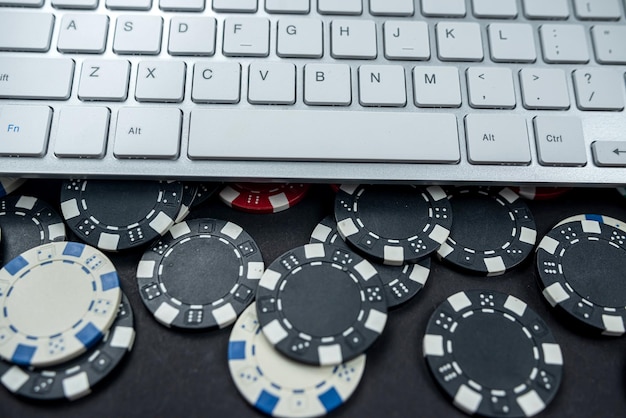 Teclado de computador ou laptop com fichas de pôquer colocadas em um fundo liso isolado Conceito de apostas de cassino on-line na Internet Jackpot chips casino