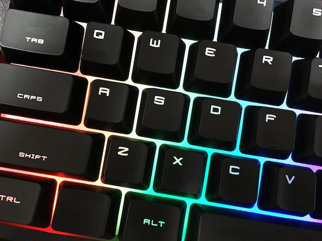 Teclado de jogo moderno com teclas retroiluminadas brilhantes em cima da mesa