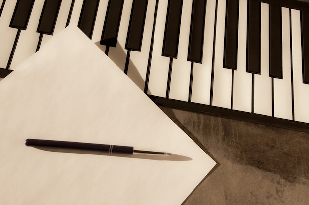 Teclado de piano, caneta e papel em branco. O conceito de compor música, canções, criatividade, aprendizagem.