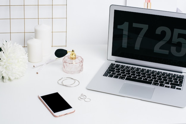 Teclado de telefone e laptop de tela em branco na mesa branca com flor branca