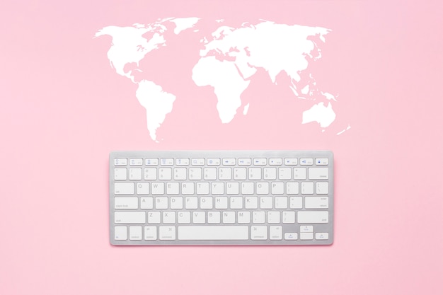 Teclado em um fundo rosa. Mapa mundial. Rede global de conceito, comunicação com o mundo, em qualquer lugar do mundo. Vista plana leiga, superior.