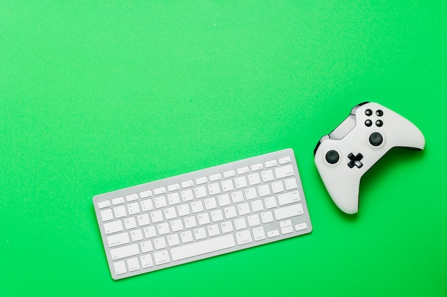 Teclado y gamepad sobre un fondo verde. El concepto del juego en la consola, juegos en línea. Vista plana, vista superior.