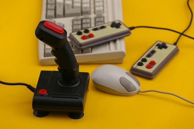 Teclado, joystick, gamepad y mouse antiguos sobre fondo azul. Juegos retro. Años 80.