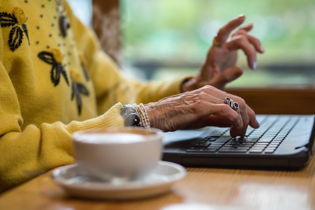 Teclado y manos de mujer senior