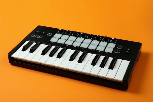 Teclado midi sobre fondo naranja, instrumento musical digital