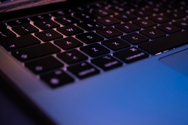 Teclado moderno de computadora portátil delgada con luz de fondo en la oficina de medianoche Concepto de trabajo desde casa