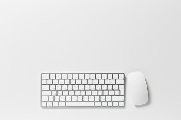 Teclado y mouse de computadora encima del escritorio blanco