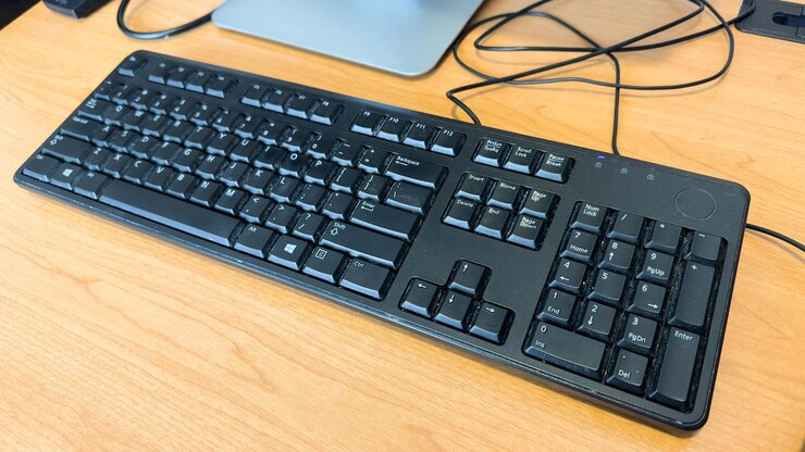 Foto un teclado negro sobre una mesa de madera con las letras q y q.