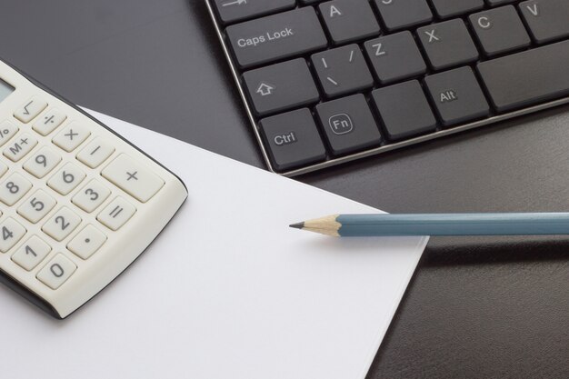 Teclado, notebook e calculadora em cima da mesa, vista superior