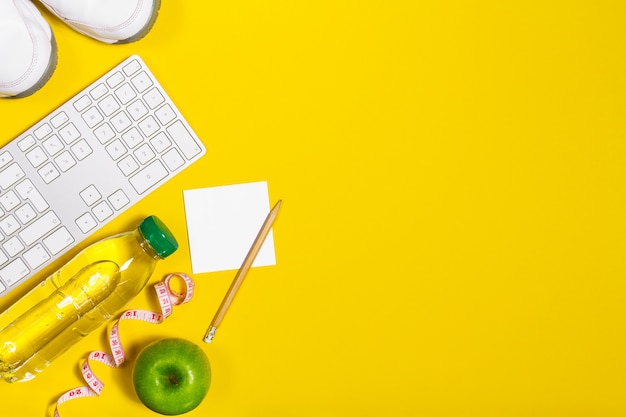 Teclado de ordenador con fruta y una botella de agua