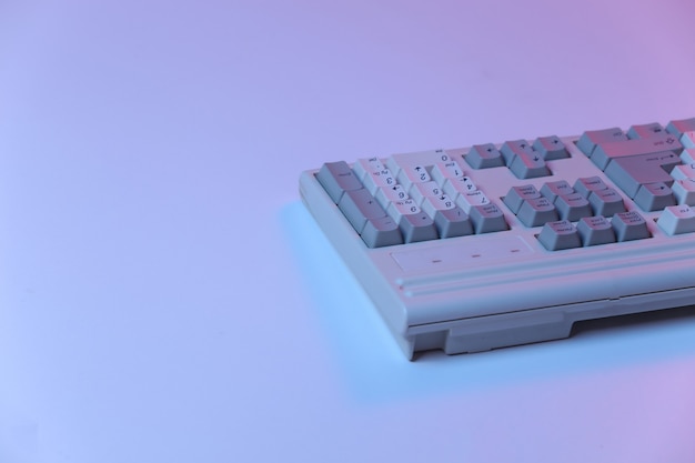 Teclado de pc antiguo en neón degradado azul rosa, luz holográfica.