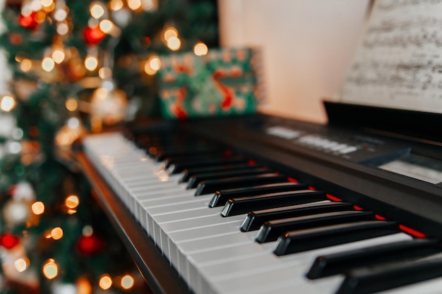 Teclado de piano con brillantes luces navideñas en el fondo