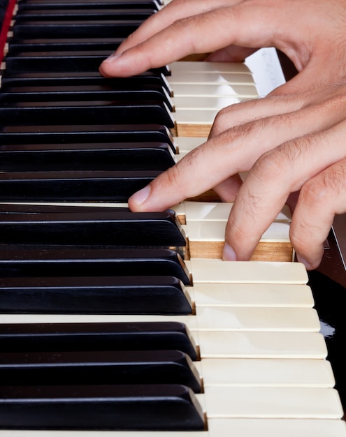 Teclado de piano hecho de marfil con manos.